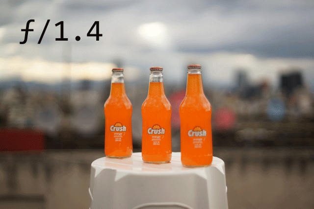 Aperture comparison showing three orange bottles photographed at different f-stops, with changes in background sharpness.
